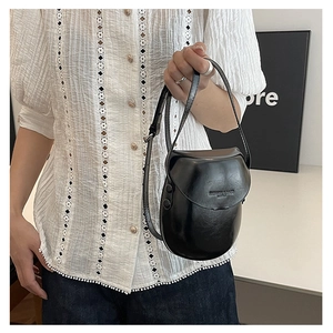 Close-up of black shell saddle bag with polished finish and fashion text detailing