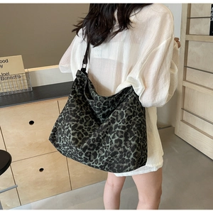 Detailed view of large leopard print canvas hobo bag worn by model in a natural indoor setting