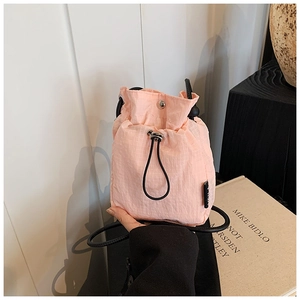 Close-up of pink nylon drawstring bucket bag with grid texture and metal snap closure
