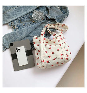 Detail of strawberry pattern on cream corduroy tote bag with daily essentials