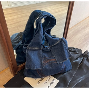 Detail of blue denim tote bag with orange stitched circles and a wide shoulder strap