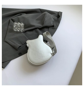 Detailed view of silver guitar-shaped shoulder bag with smooth metallic finish and wide strap