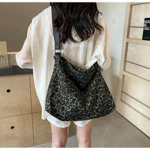 Detail of green leopard canvas hobo bag with a brown leather adjustable strap on model