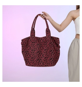 Detailed view of large leopard print tote bag being held by a model for size perspective