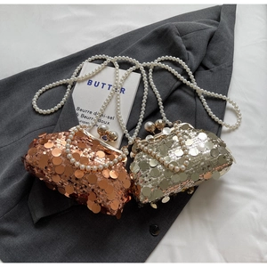 Close-up of bronze and gold sequin clutch bags with pearl chains and vintage metal clasps