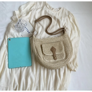 Detailansicht der Strohtasche mit Leder-Schnalle und Tasche auf weißem Stoffgewebe