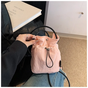 Close-up of pink mini nylon drawstring bucket bag with black strap and metallic toggle