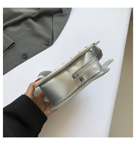 Close-up of metallic silver guitar-shaped bag with unique wing details and wide strap