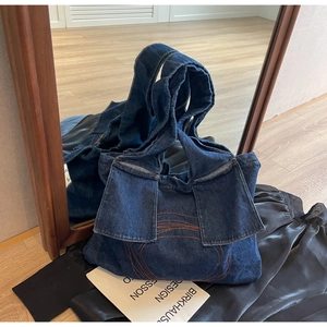 Detail of navy blue denim tote bag with orange contrast stitching and rectangular pockets