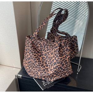 Close-up of leopard print tote bag fabric and dual shoulder straps on a mirror display