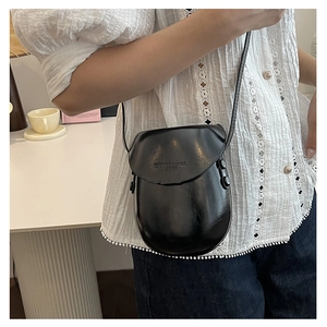 Detail of black glossy saddle bag with embossed letters and adjustable shoulder strap