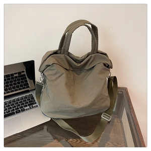 Détail d'un sac cabas en nylon vert olive avec bandoulière large et crochets métalliques