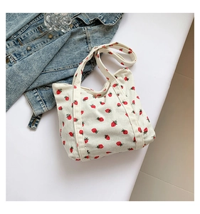 Detail of white corduroy tote bag with red strawberry print and soft ribbed texture