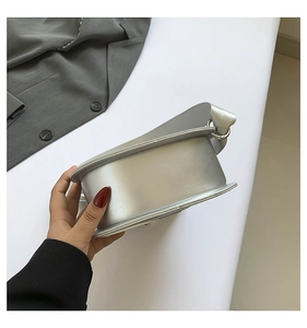 Detailed side view showing silver guitar-shaped shoulder bag stitching and curved bottom