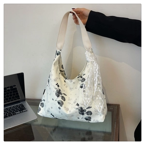 Détail du sac fourre-tout à fleurs avec brides beige, écharpe en dentelle et capacité