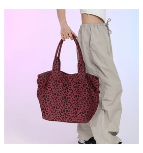 Detail of trendy leopard print tote bag in wine red canvas held by a casual model