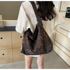 Detail view of large leopard print canvas tote bag with wide leather strap on shoulder