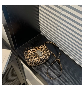 Close-up of leopard print saddle bag with vintage silver buckle and light shadows