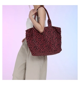 Model wearing a burgundy leopard print tote bag against a pastel studio backdrop