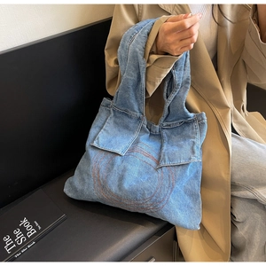 Detail of blue denim tote bag featuring handmade geometric stitching and soft texture