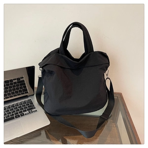 Détail d'un grand sac fourre-tout noir avec poignées épaisses et bandoulière réglable