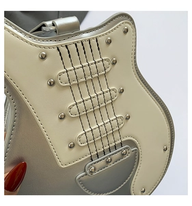 Detailed close-up of guitar-shaped handbag with metallic studs and silver leather finish
