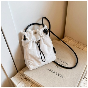 Close-up of white drawstring nylon bucket bag placed on art books with minimalist aesthetic