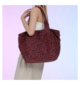 Detail of a large leopard print canvas tote bag shown with shoulder strap on a model