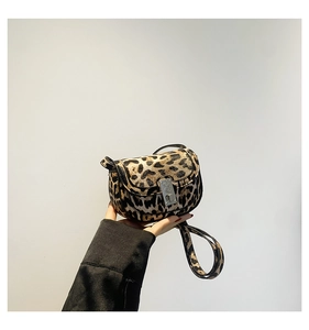 Detail view of leopard print saddle bag featuring a silver metal flap lock and long strap