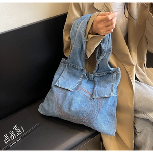Detailed macro view of blue denim tote bag featuring decorative circular embroidery