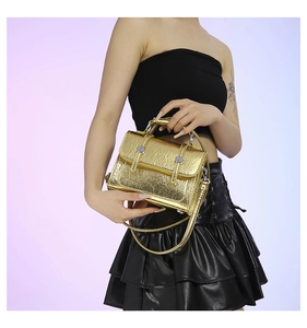Detail of metallic gold pleated texture and silver round hardware on small crossbody bag