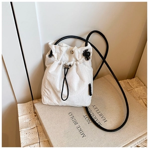 Detail of white nylon drawstring bucket bag with grid texture on artistic books