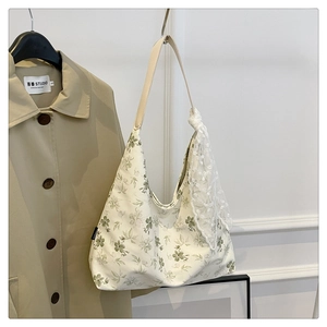 Détail d'un sac cabas à fleurs avec foulard en dentelle et bandoulière en similicuir
