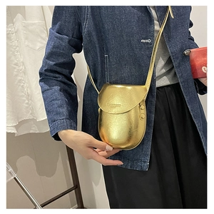 Detailed view of mini metallic gold saddle bag featuring embossed fashion text and slim strap