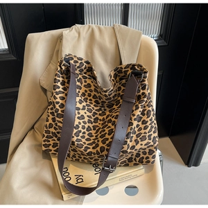 Detail of leopard print canvas tote bag featuring adjustable dark brown leather strap