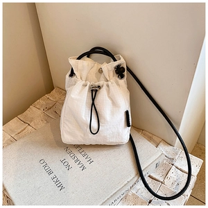 Detail of white checkered nylon bucket bag with black drawstring closure and shoulder strap