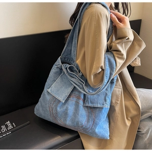 Detail of classic blue denim tote bag with concentric circle stitching and wide shoulder strap