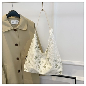 Détail d'un cabas floral en toile avec un nœud en dentelle blanche sur la bandoulière