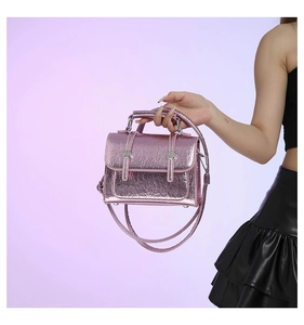 Close-up of metallic pink messenger bag featuring textured finish and silver buckles