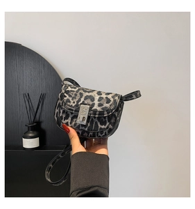 Close-up of leopard print saddle bag with vintage silver metal buckle and soft texture