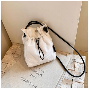 Detail of white nylon drawstring bucket bag with grid texture and silver metal eyelets