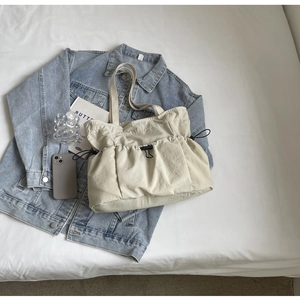 Detailed macro view of beige canvas tote bag featuring adjustable drawstring pleated pockets