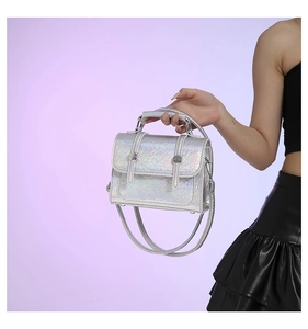 Macro detail of silver holographic leather texture and metallic clasp on messenger bag