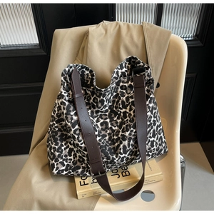 Detail of leopard print canvas hobo bag showing texture and wide leather shoulder strap