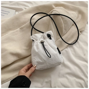Close-up of white drawstring nylon crossbody bag with black straps and metal buckle