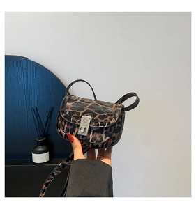 Detail of leopard print crossbody bag featuring an ornate silver floral engraved buckle lock