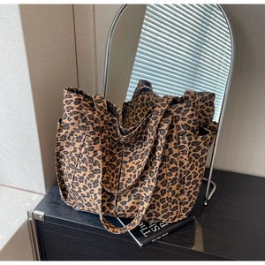 Dettaglio della borsa tote in tela leopardata con doppi manici e tasche laterali