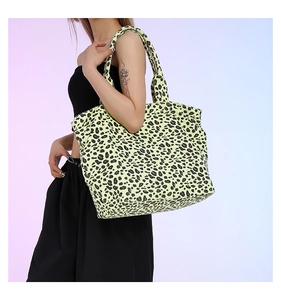 Detail of large leopard print tote bag in neon yellow worn over the shoulder by a model