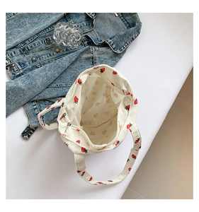 Detail of white corduroy tote bag with strawberry print and smooth silver zipper