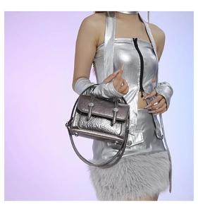 Detail of silver metallic wrinkled texture and cylindrical buckle on futuristic bag